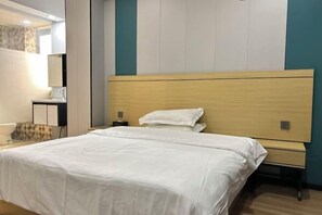 Una habitación de hotel con una cama grande, una mesita de noche y un baño con lavabo y espejo.