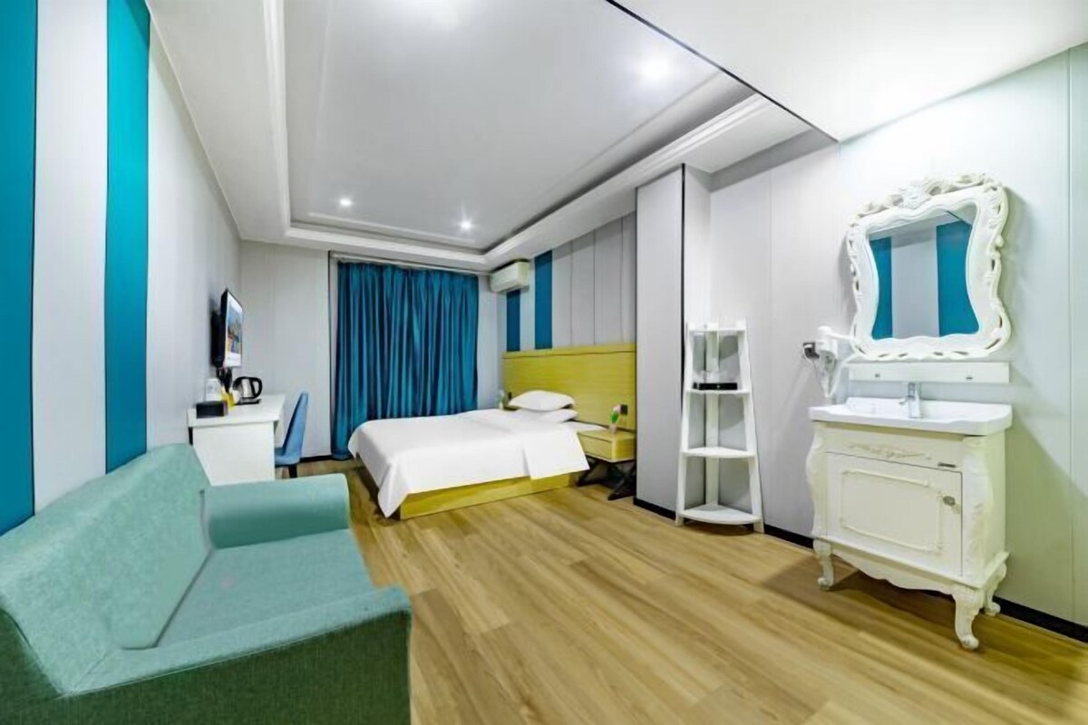 Una habitación de hotel moderna con cama, escritorio, silla, tocador con espejo y armario.