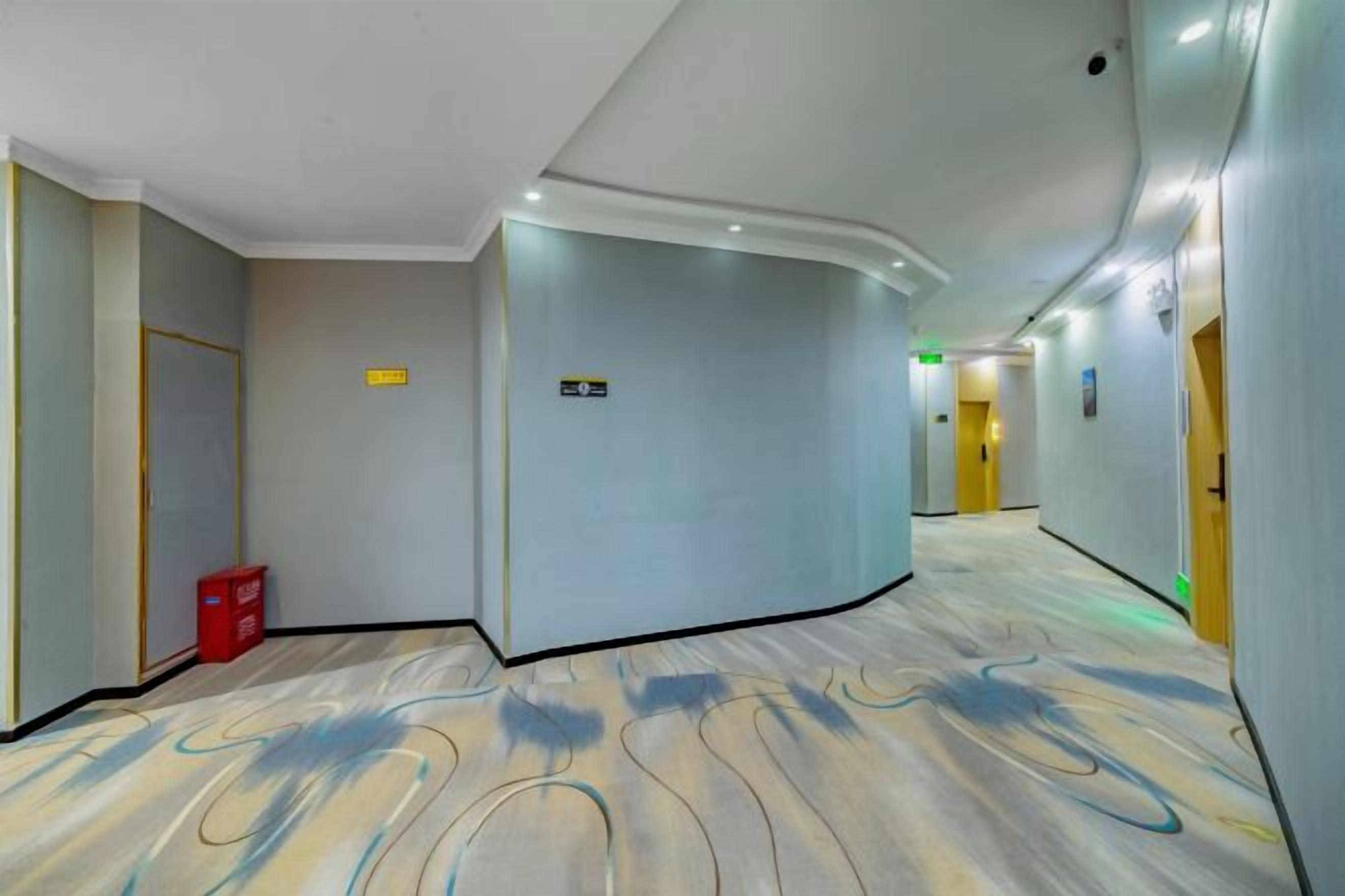 A hotel corridor with a curved ceiling, a red trash bin, and directional signs.