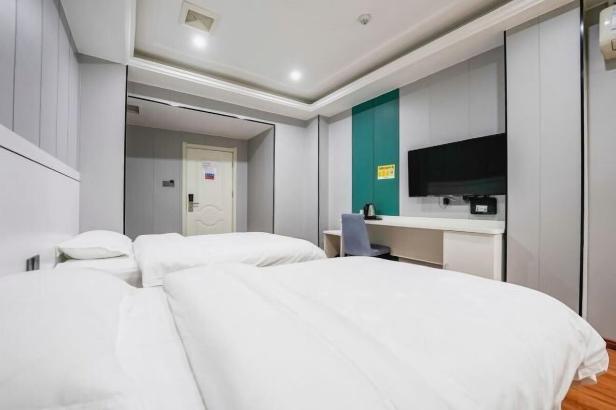 Una habitación de hotel con cama, escritorio, televisión y armario.
