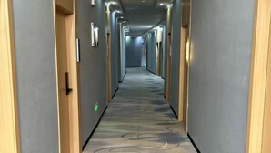 A long, narrow hallway with a patterned carpet and wooden paneling on the walls. - Core Clould of hotel (Nanchang County)