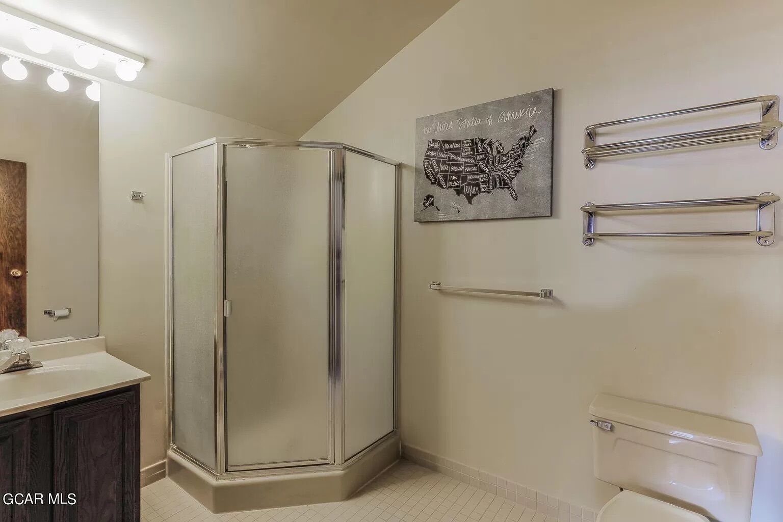 A bathroom with a glass shower enclosure, a sink with a mirror, a toilet, and a wall-mounted towel rack.