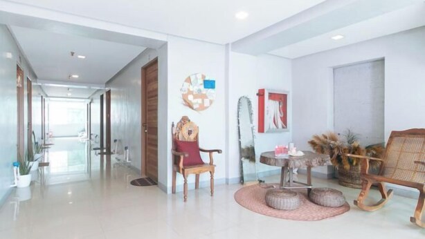 A spacious hallway with a wooden door at the end, a seating area with a round table and chairs, and a wall-mounted artwork. - Budget Backpackers Transient House Near Naia by RedDoorz (Pasay)