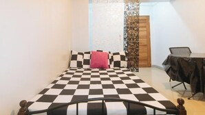 A bedroom with a checkered bedspread, a wooden headboard, a desk with a chair, and a decorative partition. - Budget Backpackers Transient House Near Naia by RedDoorz (Pasay)
