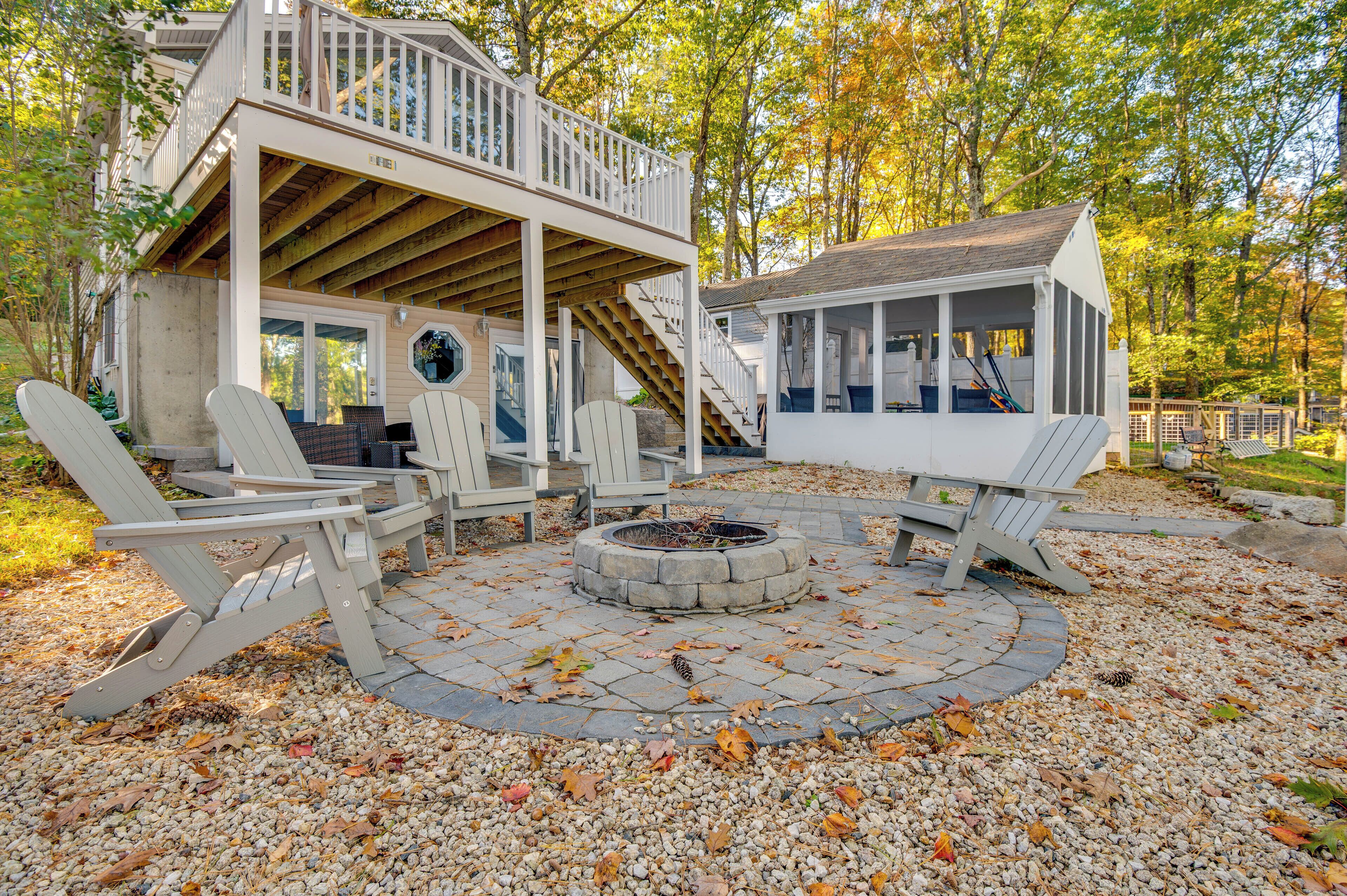 A cabin with a deck, outdoor seating, and a fire pit.