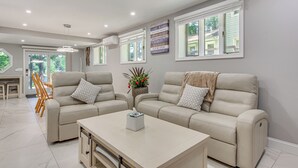 En moderne stue med to beige sofaer, et sofabord og et spiseområde med træstole.