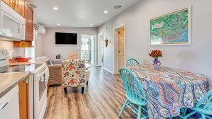 A modern kitchen with wooden cabinets, a microwave, and a dining area with a colorful tablecloth and teal chairs. - 2 Mi to Moody Beach, Amenity Access: Wells Getaway (Wells)