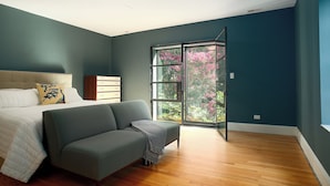 A bedroom with a bed, a sofa, a dresser, and a large window with a view of pink flowers. - Spacious Converted Carriage House in Historic District near USNA (Annapolis)