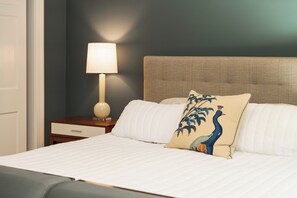 A neatly made bed with white linens and a decorative pillow featuring a peacock design. - Spacious Converted Carriage House in Historic District near USNA (Annapolis)
