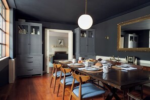 A dining area with a wooden table set for four, surrounded by chairs with blue cushions. - Spacious Converted Carriage House in Historic District near USNA (Annapolis)
