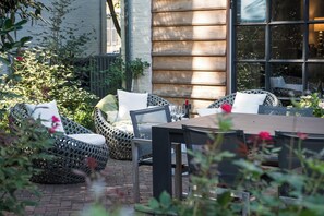 An outdoor patio with wicker furniture, a table, and a brick floor. - Spacious Converted Carriage House in Historic District near USNA (Annapolis)