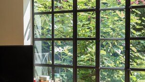 A room with a large window, a flat-screen TV, and a small wooden table. - Spacious Converted Carriage House in Historic District near USNA (Annapolis)