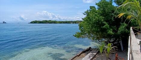A wooden deck with a clear view of the ocean and a distant island.