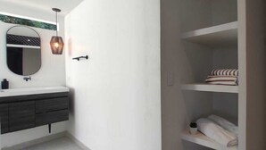 A bathroom with a white vanity, a round mirror, and a hanging light fixture. - Rosario Ecohotel  (Rosario Islands)