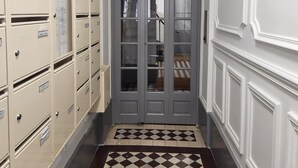 A hallway with beige filing cabinets, a checkered rug, and a gray door with glass panels.