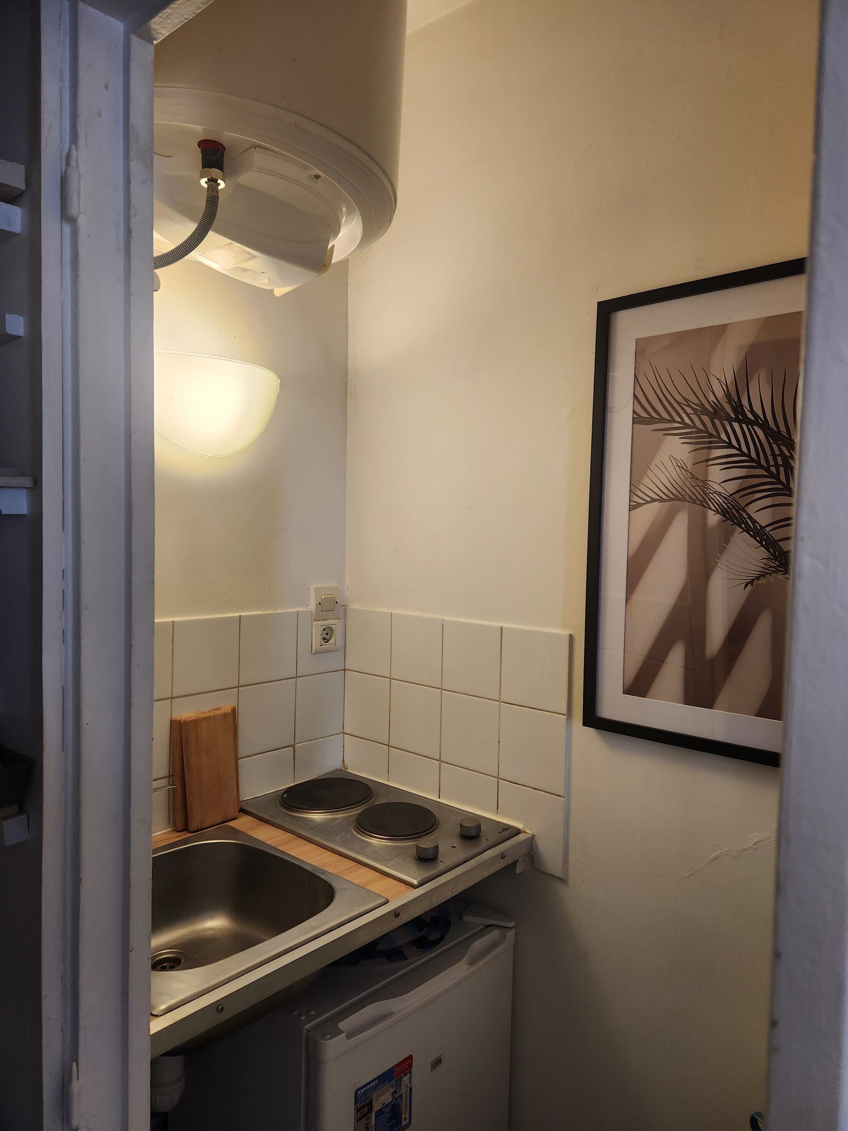 Cocina compacta con un lavamanos, dos hornillas y un refrigerador pequeño.