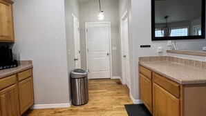 Una cocina moderna con armarios de madera, un bote de basura de acero inoxidable y una encimera negra.