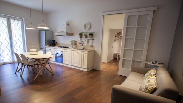 Une cuisine moderne avec un plancher en bois, un coin repas avec une table ronde et des chaises, et un salon avec un canapé.