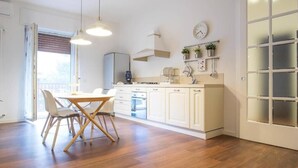 Une cuisine moderne avec des meubles blancs, une table à manger avec des chaises et une horloge au mur.