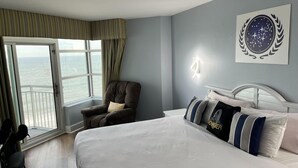 Une chambre à coucher avec un grand lit, une chaise, une table de chevet et une lampe fixée au mur.