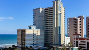 Un hôtel de grande hauteur, avec de nombreux étages, une tour imposante et une vue sur l’océan.