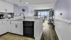 Une cuisine moderne avec des meubles blancs, un lave-vaisselle et une vue sur le salon.