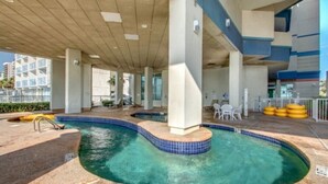 Un espace extérieur avec une piscine, une terrasse en béton, une petite pataugeoire et quelques chaises longues.