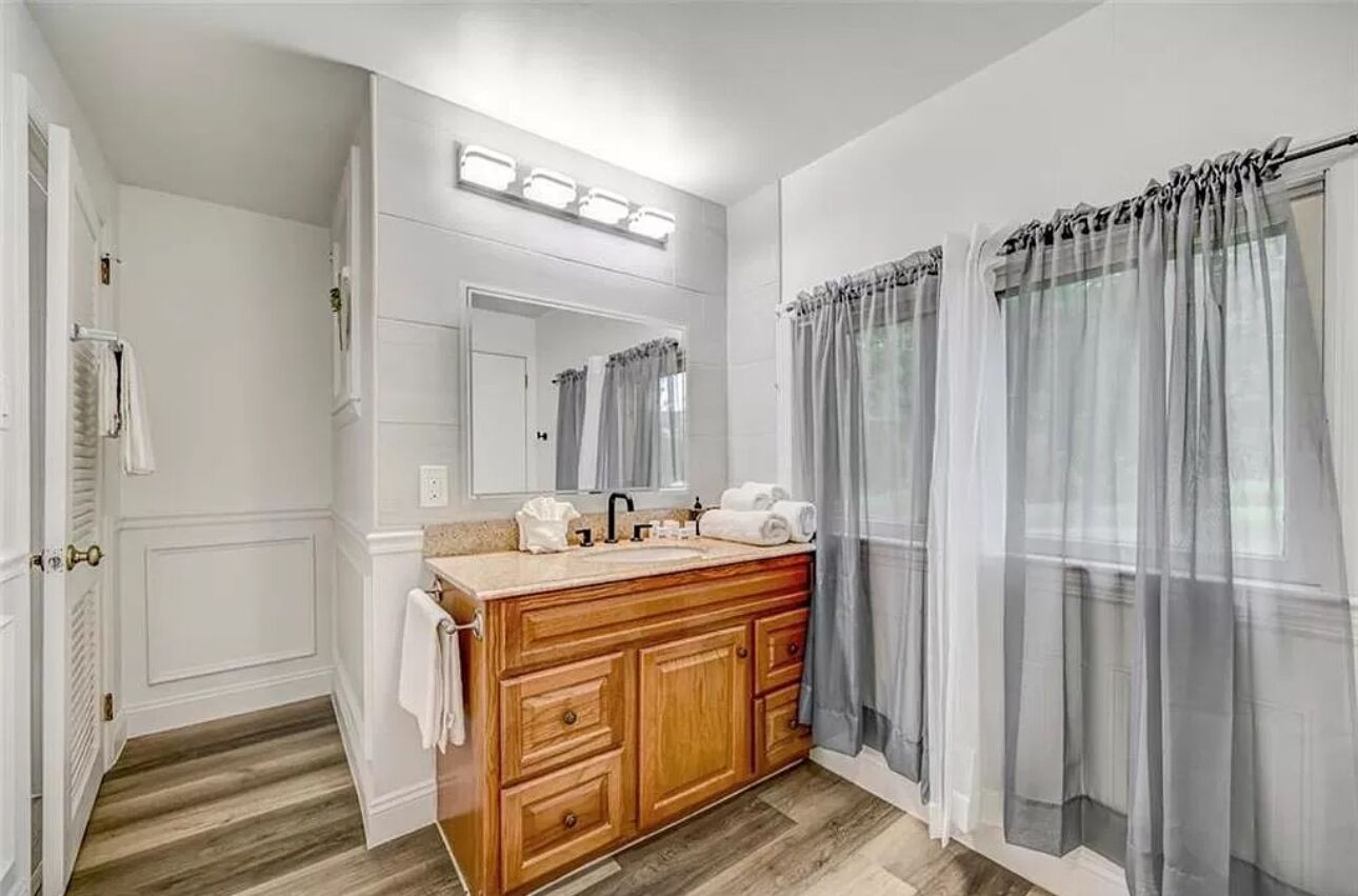 A bathroom with a wooden vanity, a mirror, and a shower curtain.