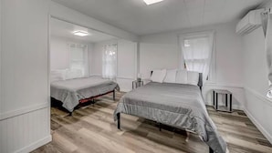 Ein Schlafzimmer mit zwei Einzelbetten, einem großen Bett und einem Fenster.