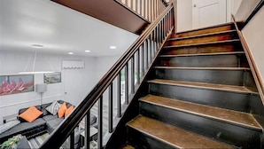 Eine Treppe mit hölzernem Geländer und Metallspindeln, die zu einer oberen Etage führt.