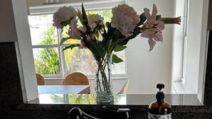 Una cocina con dos lavamanos de acero inoxidable, una botella de jabón líquido y un florero con flores en la encimera.