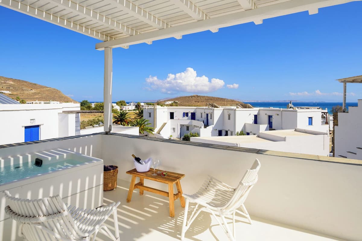 Une terrasse sur le toit avec une piscine, une table avec une bouteille et des verres, et des chaises en osier blanc.