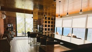 A modern bar area with wooden flooring, a counter with stools, and large windows offering a view of the city. - Redibuk - Beautiful apart 2 BR Barranco (Lima)