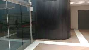A modern interior with a curved black partition, glass doors, and a tiled floor. - Saint Sebastian ap101-stúdio  (Jaragua do Sul)