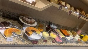 En buffé med ett varierat utbud av mat, inklusive tårtor, bakverk samt olika sorters pålägg och dippsåser.