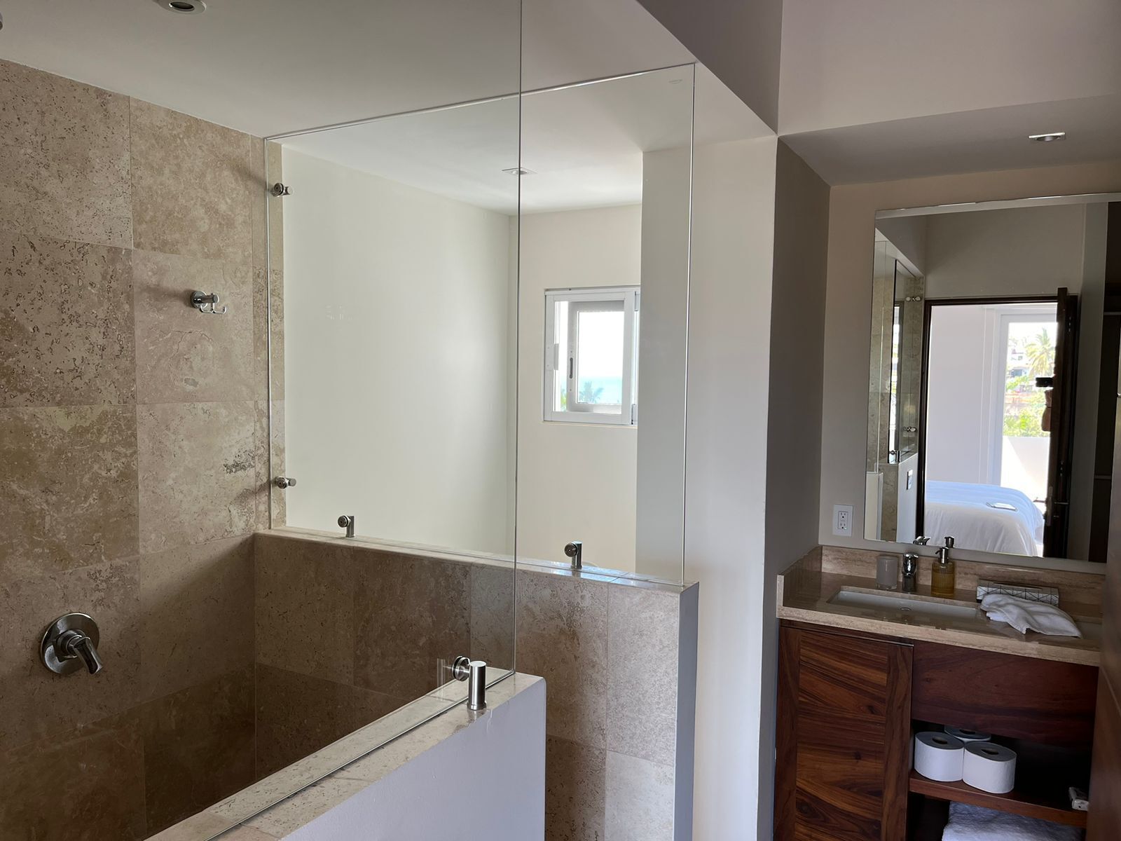 Een moderne badkamer met een douche met glazen wand, een houten wastafelmeubel en een grote spiegel.