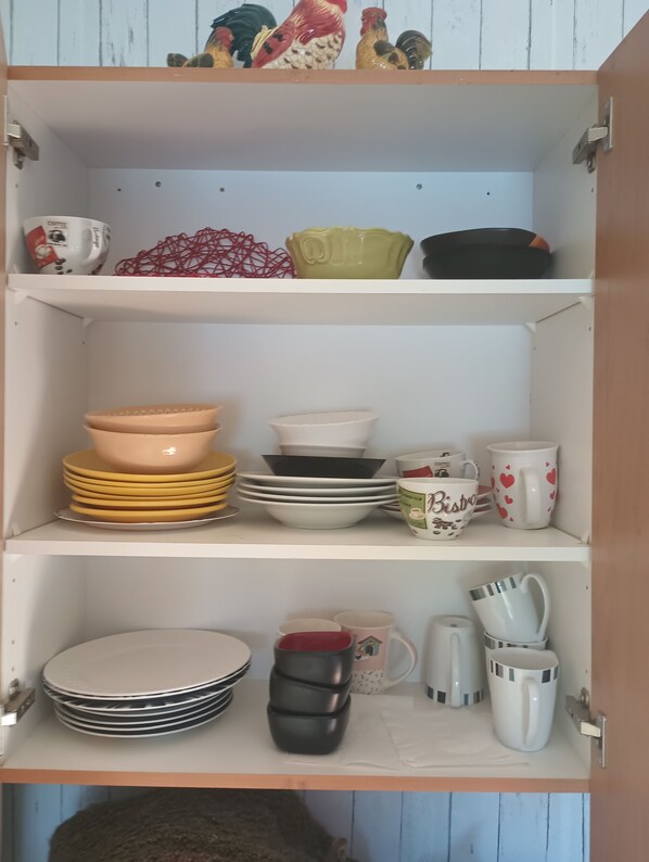 A kitchen cabinet with various dishes and utensils.