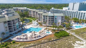 A resort with multiple buildings, a central pool area with sun loungers, and a surrounding landscape. - End Unit; Ocean Peek; 5th floor - Villamare. 2 hrs Pickleball/Tennis per day! (Hilton Head Island)