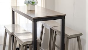 A minimalist wooden table with two benches, a vase with flowers, and a wall-mounted light fixture. - Modern Apartment in Black Rock (Bridgeport)