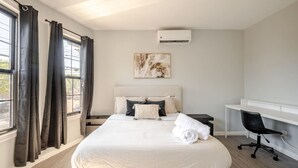 A modern hotel room with a large bed, a desk, and a chair. - Modern 3-Bdrm Apt in Black Rock (Bridgeport)