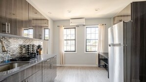 A modern kitchen with stainless steel appliances, a tiled backsplash, and large windows. - Modern 3-Bdrm Apt in Black Rock (Bridgeport)