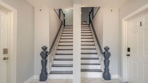 A staircase with white walls and a marble floor leading to a landing. - Modern 3-Bdrm Apt in Black Rock (Bridgeport)