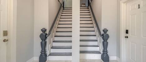 A staircase with white walls and a marble floor leading to a landing.