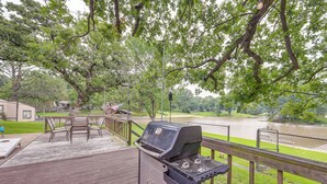 A wooden deck with a grill, outdoor furniture, and a view of a river. - Lakefront Gun Barrel City Home w/ Dock & Deck (Gun Barrel City)