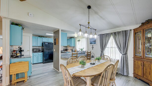 A spacious dining area with a wooden table and chairs, a kitchen with light blue cabinets, and a wooden cabinet with glass doors. - Lakefront Gun Barrel City Home w/ Dock & Deck (Gun Barrel City)