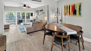 Un vaste espace de vie comprenant une table à manger, des canapés et une vue sur l’extérieur.