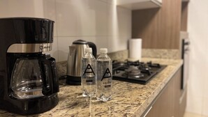 A kitchen with a coffee maker, two water bottles, and a kettle on the counter. - Redibuk - Luxury duplex 1BR Miraflores (Lima)