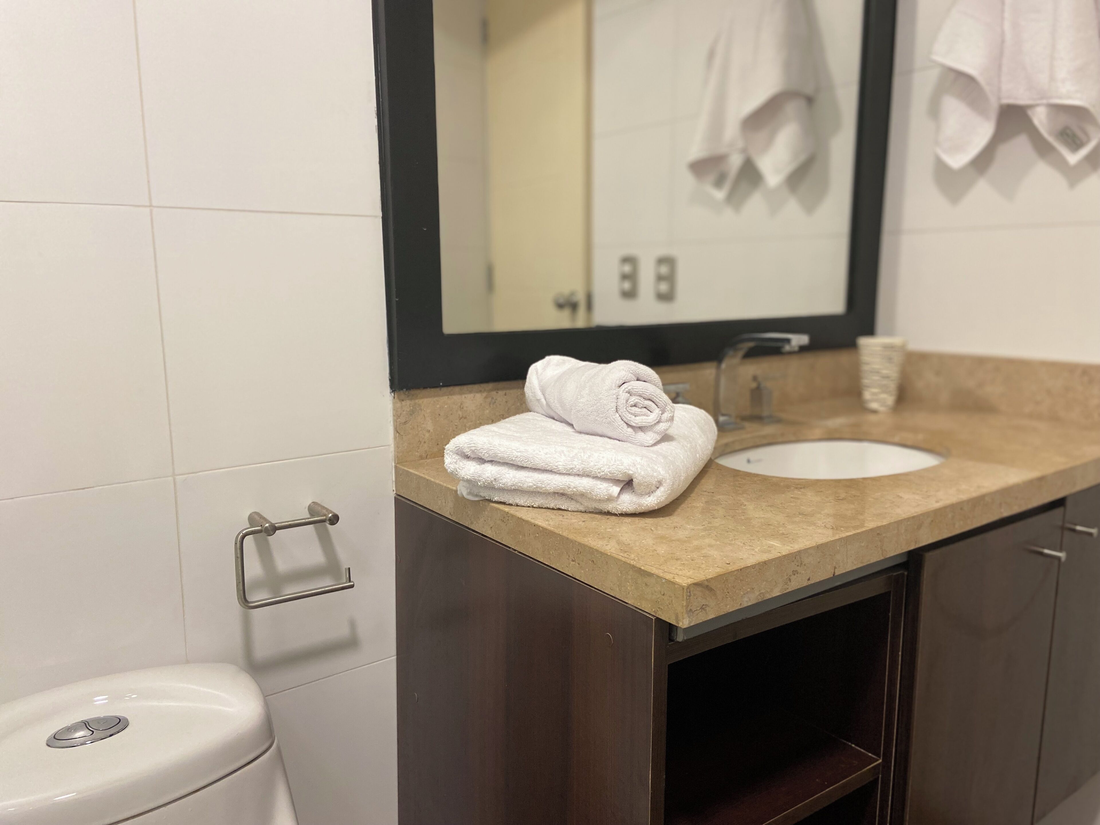 A bathroom with a white sink, a mirror, and a towel on the countertop.