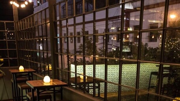 An indoor seating area with tables and chairs, large windows, and string lights. - Redibuk - Luxury duplex 1BR Miraflores (Lima)