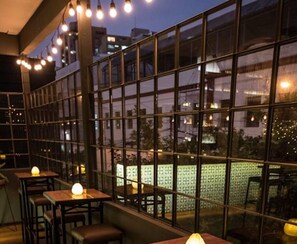 An indoor seating area with tables and chairs, large windows, and string lights. - Redibuk - Luxury duplex 1BR Miraflores (Lima)